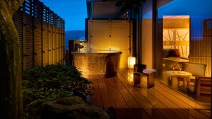 Un patio exterior moderno con un jacuzzi, terraza de madera y zona de estar con mesa y sillas.