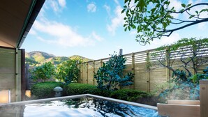 Zona de baños termales con terraza de madera, cerramiento de bambú y abundante vegetación.
