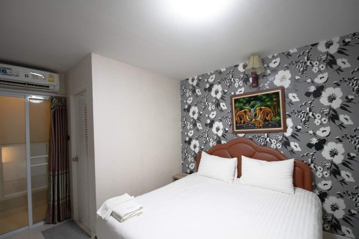 Un dormitorio con cama, zona de ducha y papel tapiz floral.