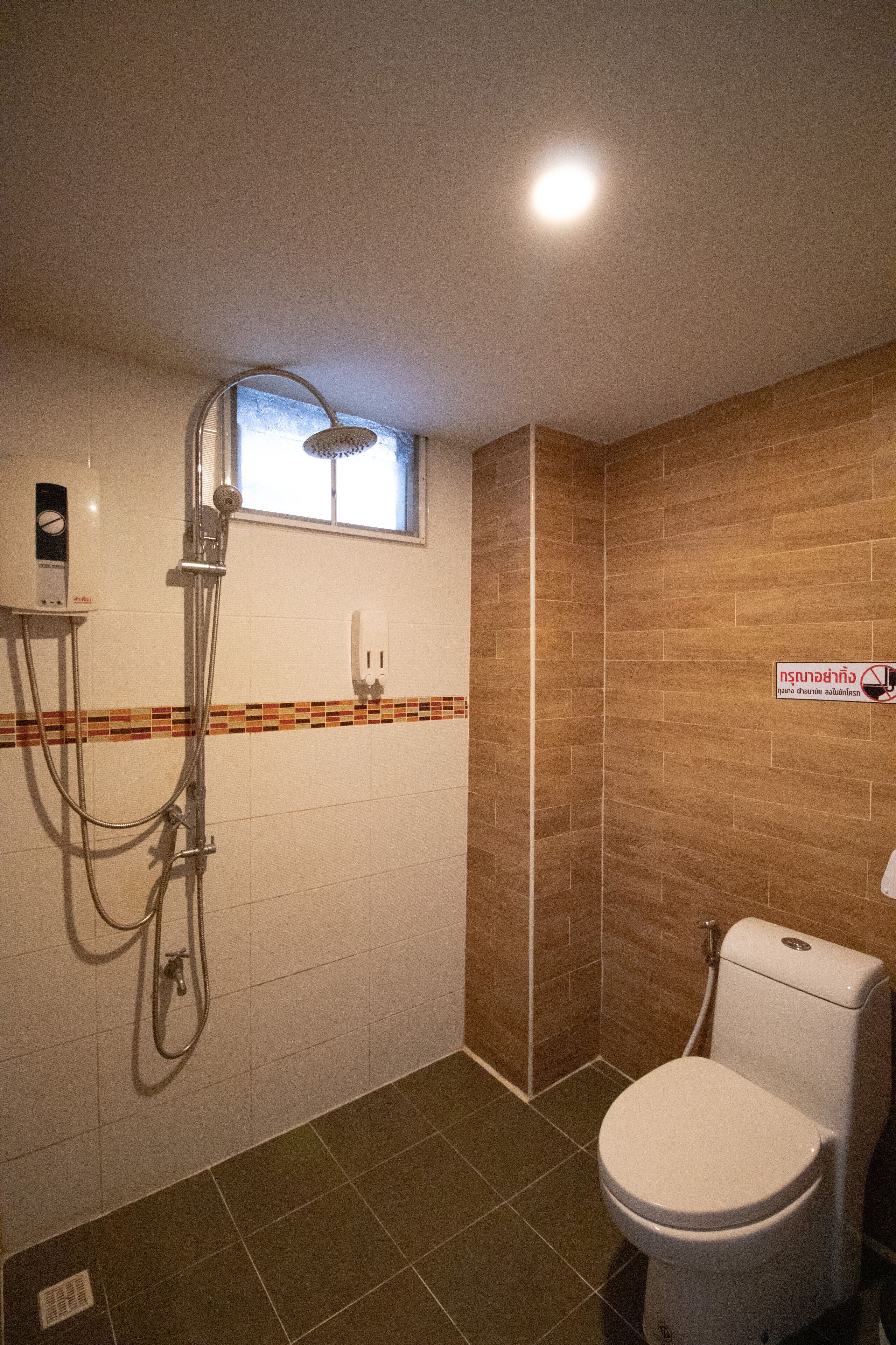 Une salle de bain avec une douche, des toilettes et une fenêtre.
