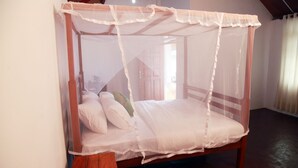A four-poster canopy bed with white linens and pillows, wooden frame, and a wooden footboard. - Sinharaja Forest Sanctuary Hotel (Deniyaya)