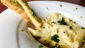 A dish of pasta with a breadstick on a white plate. - Sinharaja Forest Sanctuary Hotel (Deniyaya)