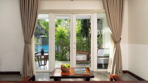 Una habitación con una mesa, un libro y vistas a una piscina y follaje exterior.