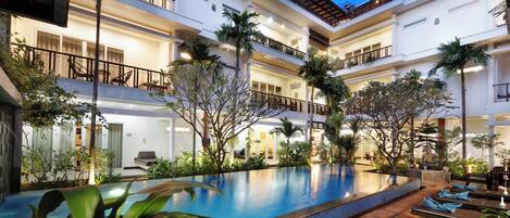 Una piscina al aire libre, sombrillas, sillones reclinables de piscina