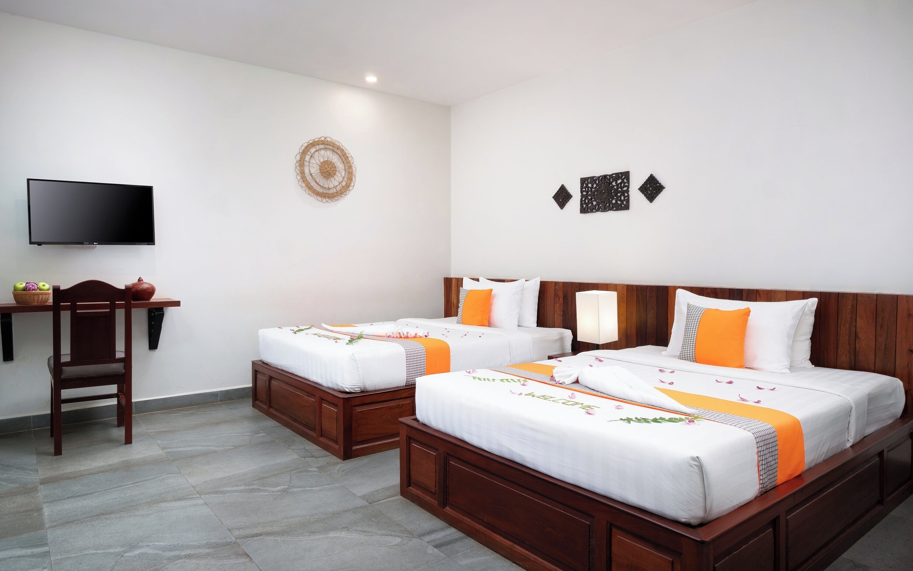 A hotel room with two beds, a TV, a wooden desk, and a chair.