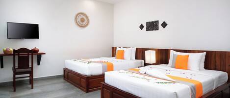 A hotel room with two beds, a TV, a wooden desk, and a chair.