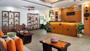 Un vestíbulo moderno con mobiliario de madera, una recepción y varios objetos decorativos.