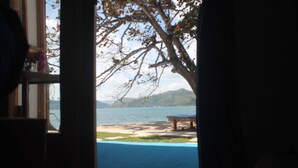 An interior room with a view of a beach and mountains through an open door. - The Place Beach Bungalows (Sekotong Barat)