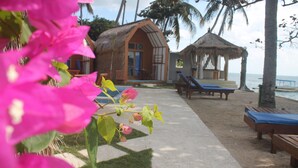 A beachside accommodation with a thatched-roof structure, lounge chairs, and a clear view of the sea. - The Place Beach Bungalows (Sekotong Barat)