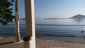 A calm lake with a clear view of distant mountains, a wooden bench, and a white column. - The Place Beach Bungalows (Sekotong Barat)