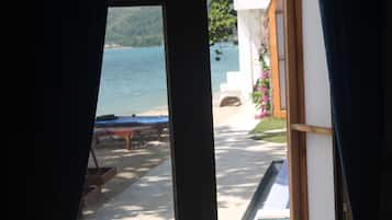 A view through a window of a pool area with a bench and a table, and a building with a white exterior and a wooden deck.