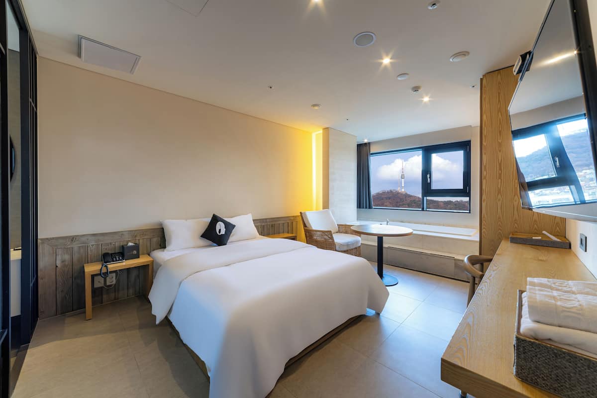 Habitació d'hotel moderna amb un llit gran, una taula de treball, una cadira i vista a les muntanyes per la finestra.