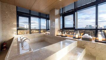 Relax in a spacious bathroom with a large bathtub and city views.