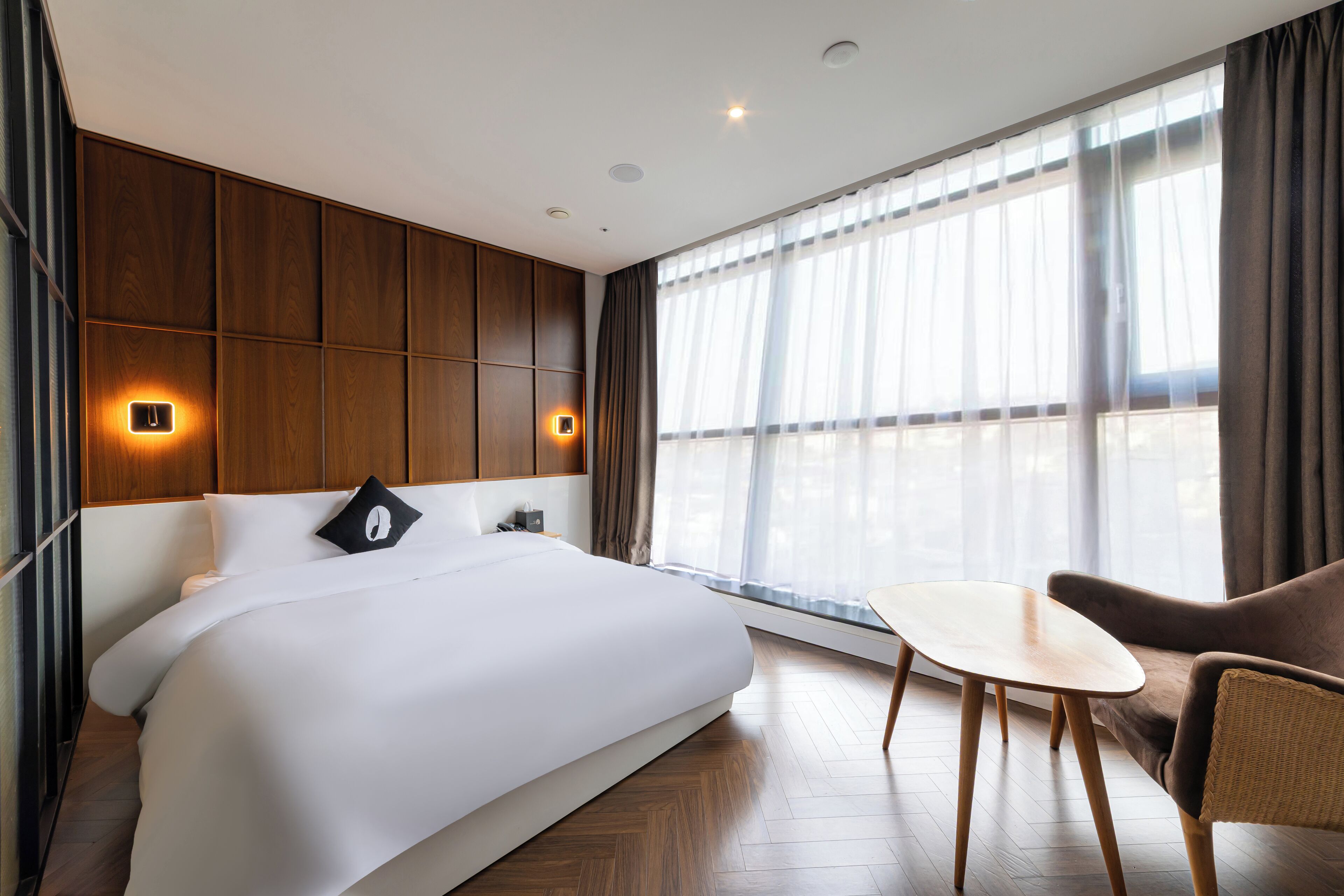 A modern hotel room with a large bed, a small table, and a sofa.