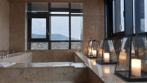 Un baño moderno con una bañera grande, una ventana con persianas y varios faroles iluminados.