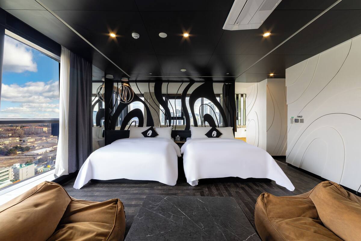 Habitació d'hotel moderna amb dos llits, vistes a la ciutat i un disseny de paret únic.