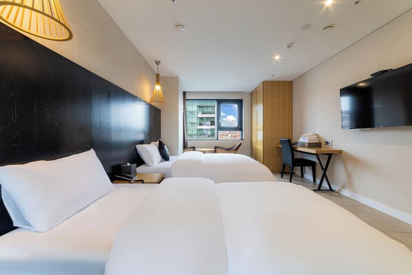 Una habitación de hotel moderna con dos camas, un escritorio, una silla, un televisor y una ventana con vistas a la ciudad.
