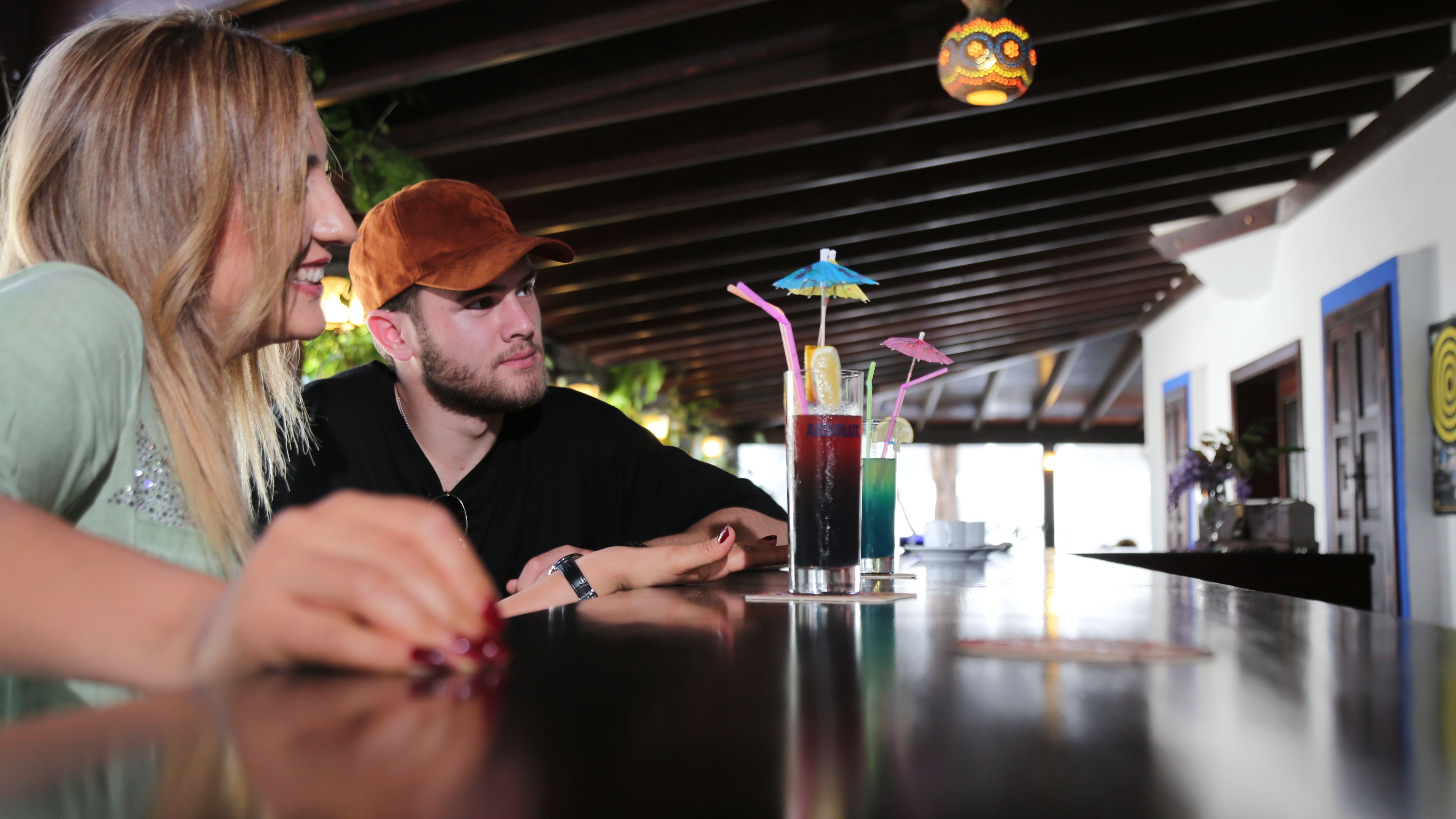 A person sitting at a bar with a drink in front of them.