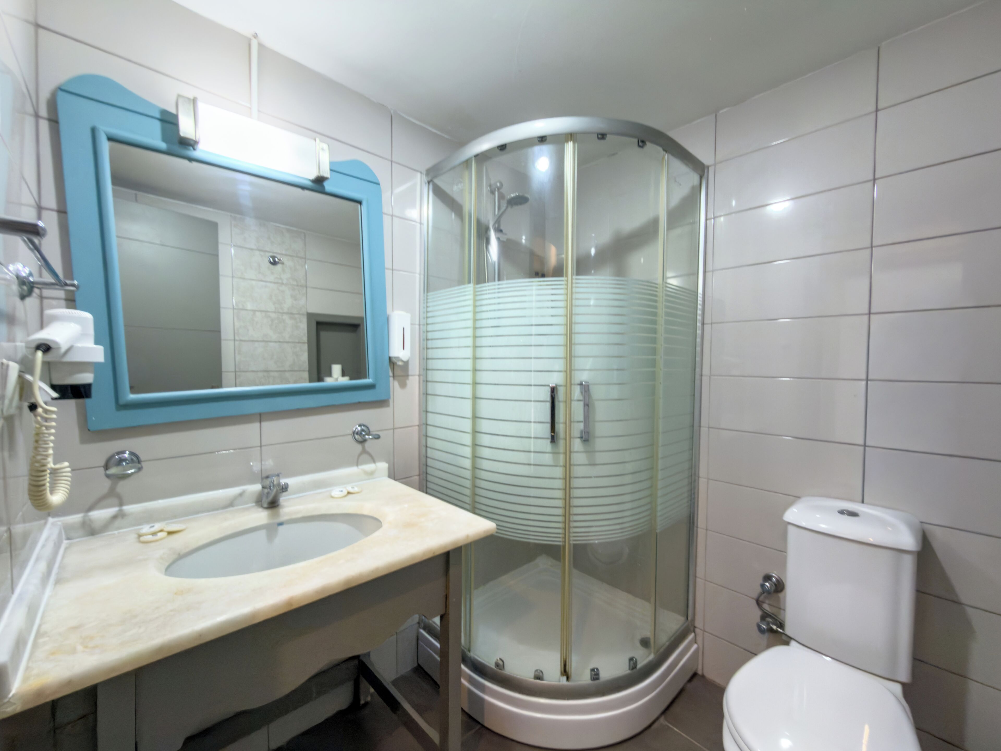A bathroom with a curved glass shower enclosure, a sink with a mirror, and a toilet.