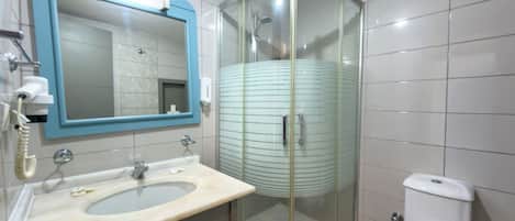 Un baño con cabina de ducha de vidrio curvo, un lavabo con espejo y un inodoro.