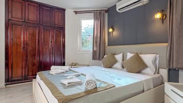 Un dormitorio con cama, armario, aire acondicionado, mesita de noche y ventana con cortinas.