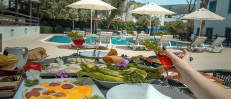 Un espace de restauration aménagé au bord de la piscine, avec une variété de plats, un verre à martini et des chaises longues.