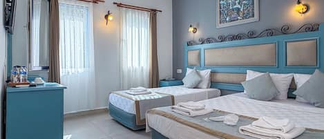 Una habitación de hotel con dos camas, un escritorio, una silla, un equipo de aire acondicionado y un cuadro en la pared.