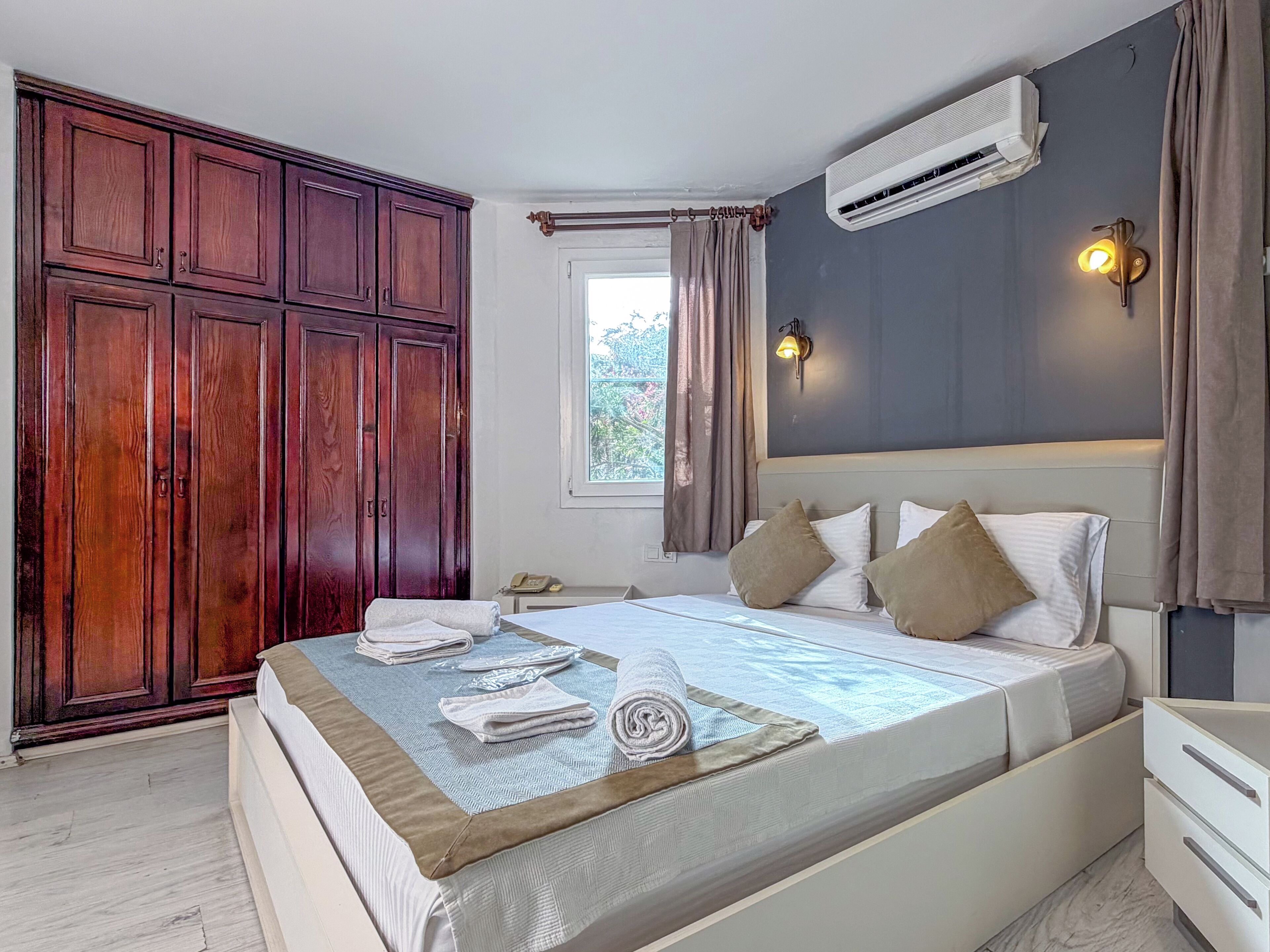 Un dormitorio con cama, armario, aire acondicionado y lámpara de noche.