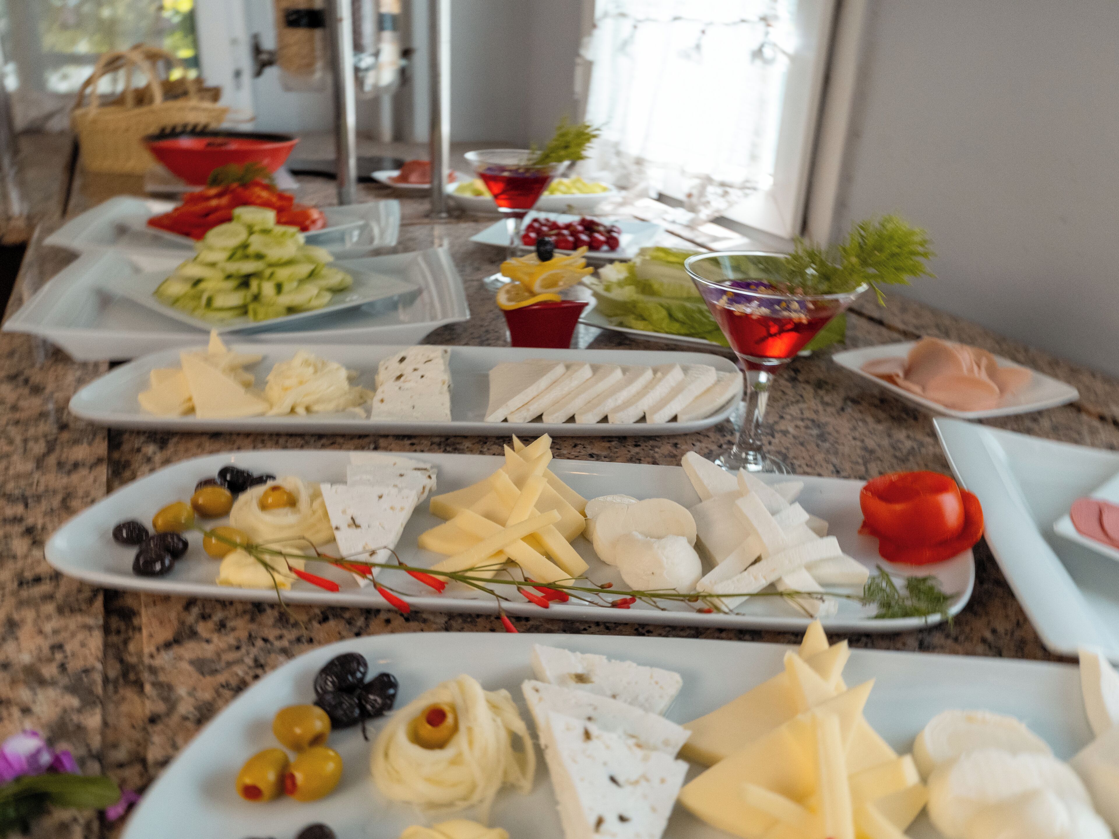 A buffet with various cheeses, olives, and fruits.