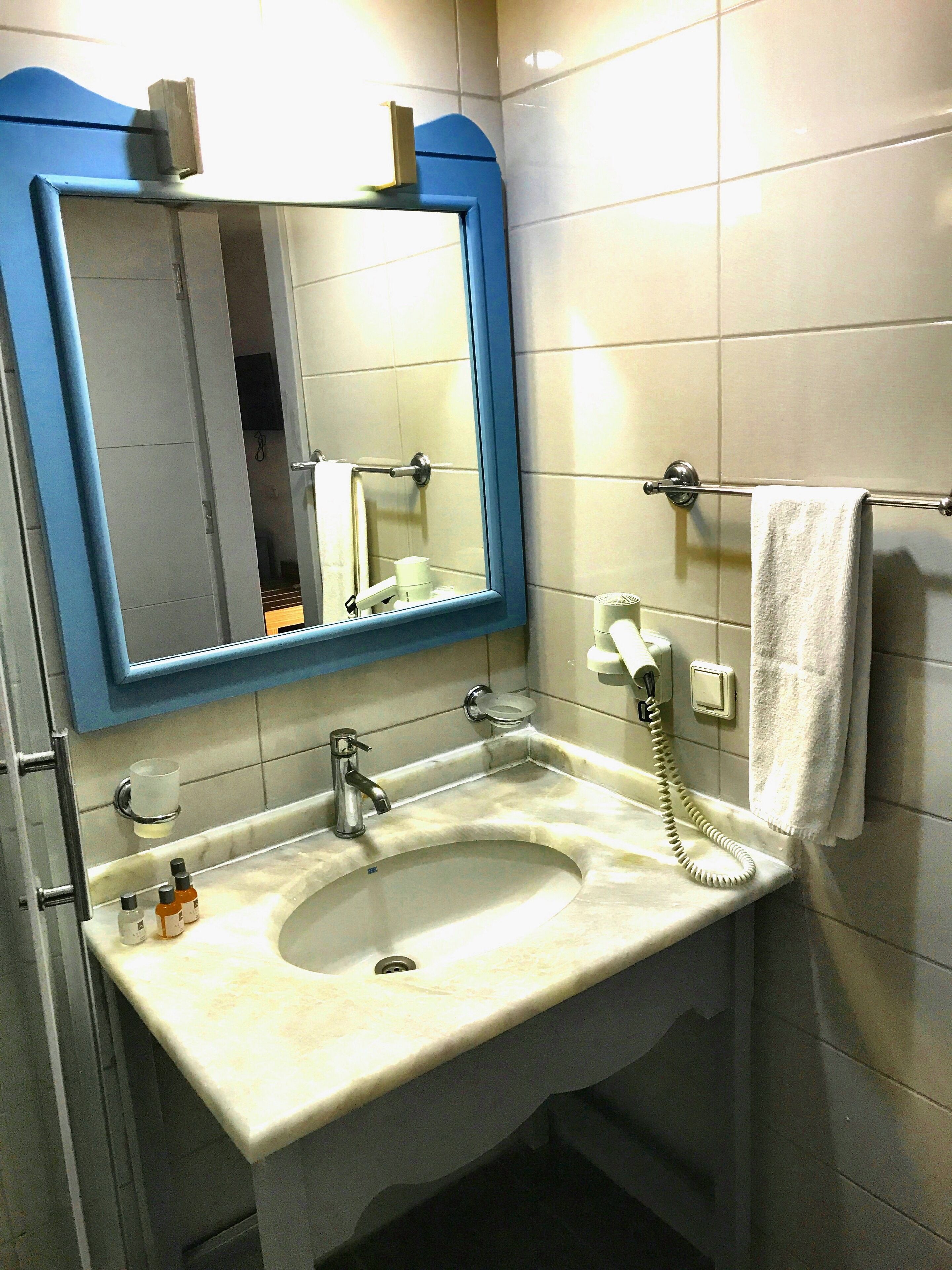 A bathroom with a sink, mirror, towel rack, and a telephone.