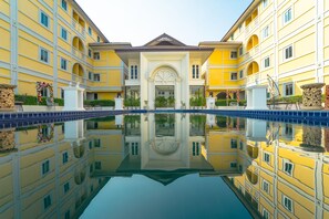 A symmetrical building with a central entrance, a courtyard, and a reflective pool. - Hotel B (Nakhon Ratchasima)