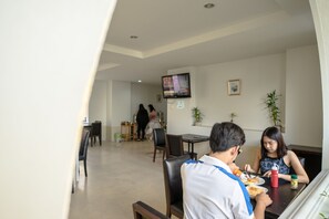 A dining area with a table, chairs, and a television mounted on the wall.