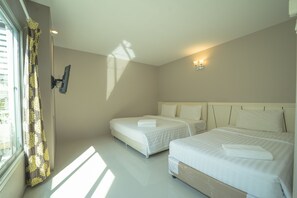 A hotel room with two beds, a window with curtains, a wall-mounted TV, and a ceiling light.