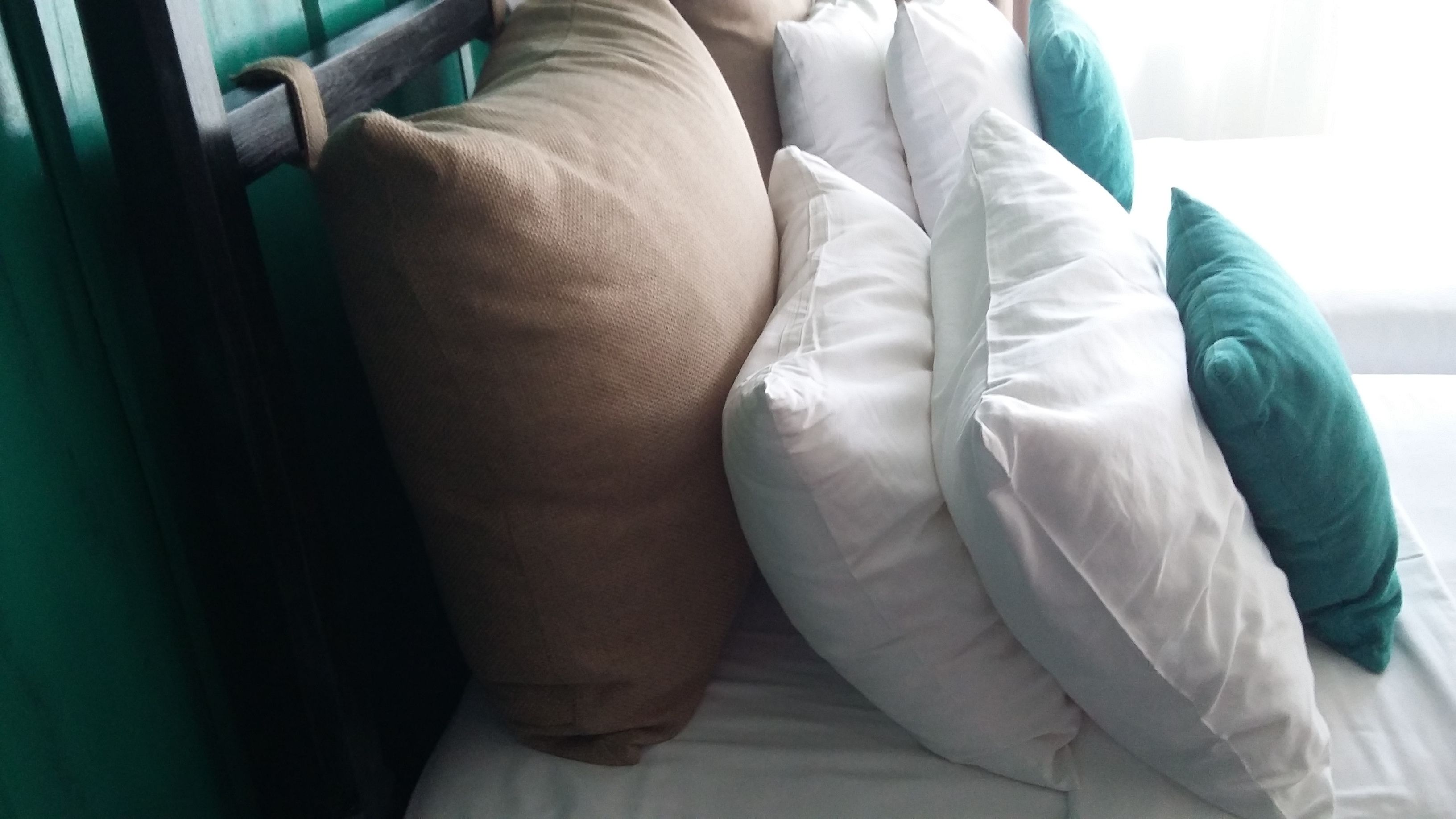 A bed with multiple pillows and a wooden headboard.