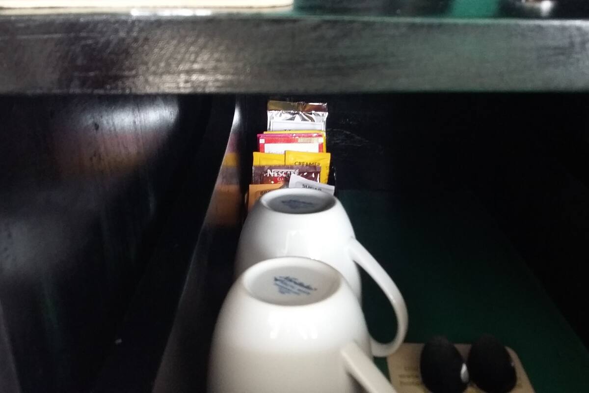 Una cafetera blanca y una taza blanca sobre una mesa.