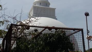 A white dome structure with a smaller building on top, surrounded by a metal fence and some greenery.