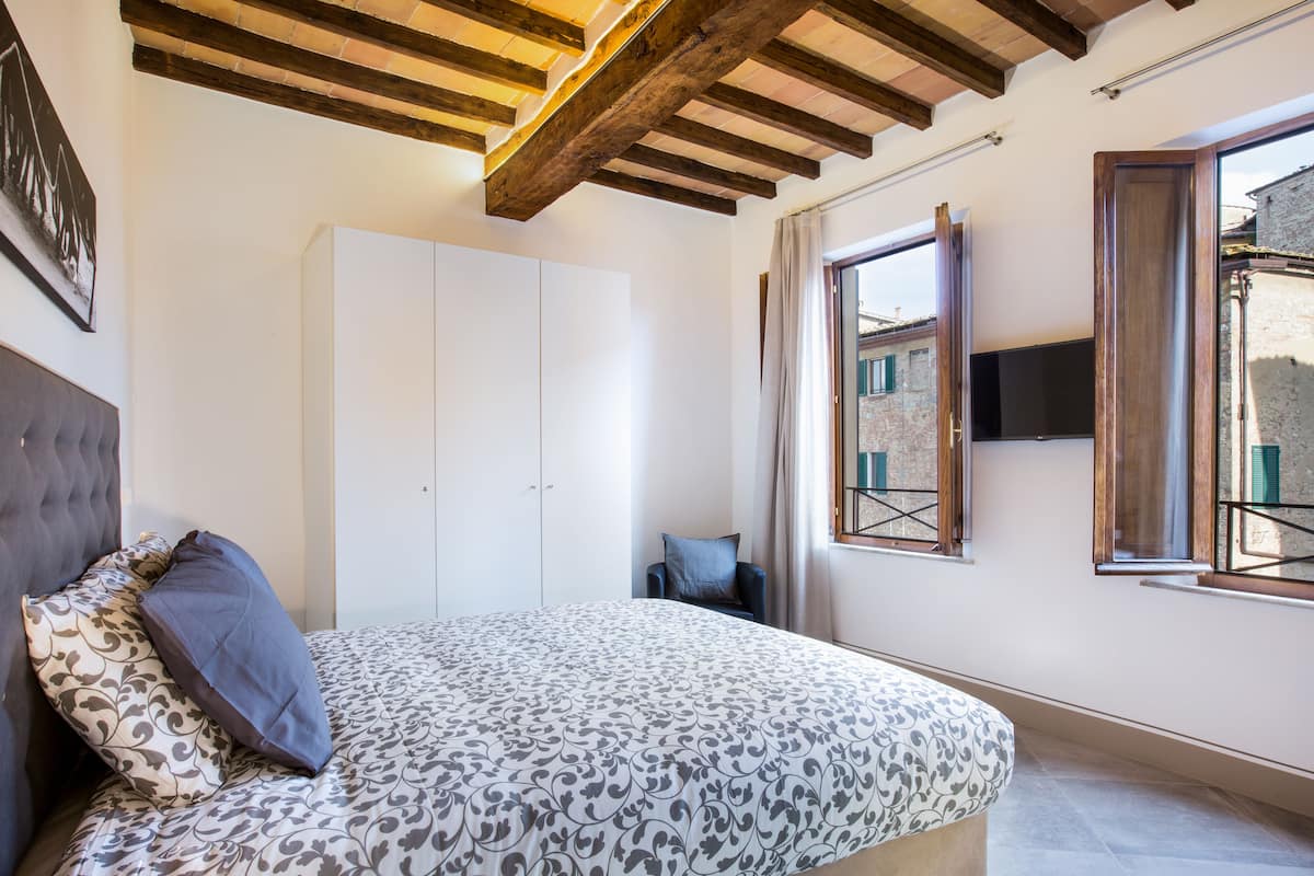 A bedroom with a bed, wardrobe, and a TV mounted on the wall.