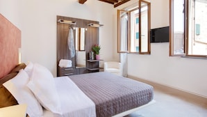 A bedroom with a bed, a mirror, a TV, and a window. - B&B Il Barbero (Siena)