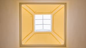 A square window with a grid pattern, framed by a decorative border, centered on a plain wall. - B&B Il Barbero (Siena)
