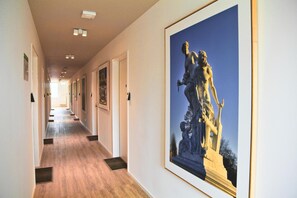 A hallway with framed artwork on the walls and a statue on the right.