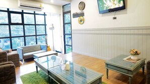 A modern living room with a glass coffee table, a sofa, and a television on the wall. - Uno Chiangmai (Chiang Mai)