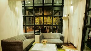 A modern living room with two grey sofas, a white coffee table, and a large window with curtains. - Uno Chiangmai (Chiang Mai)
