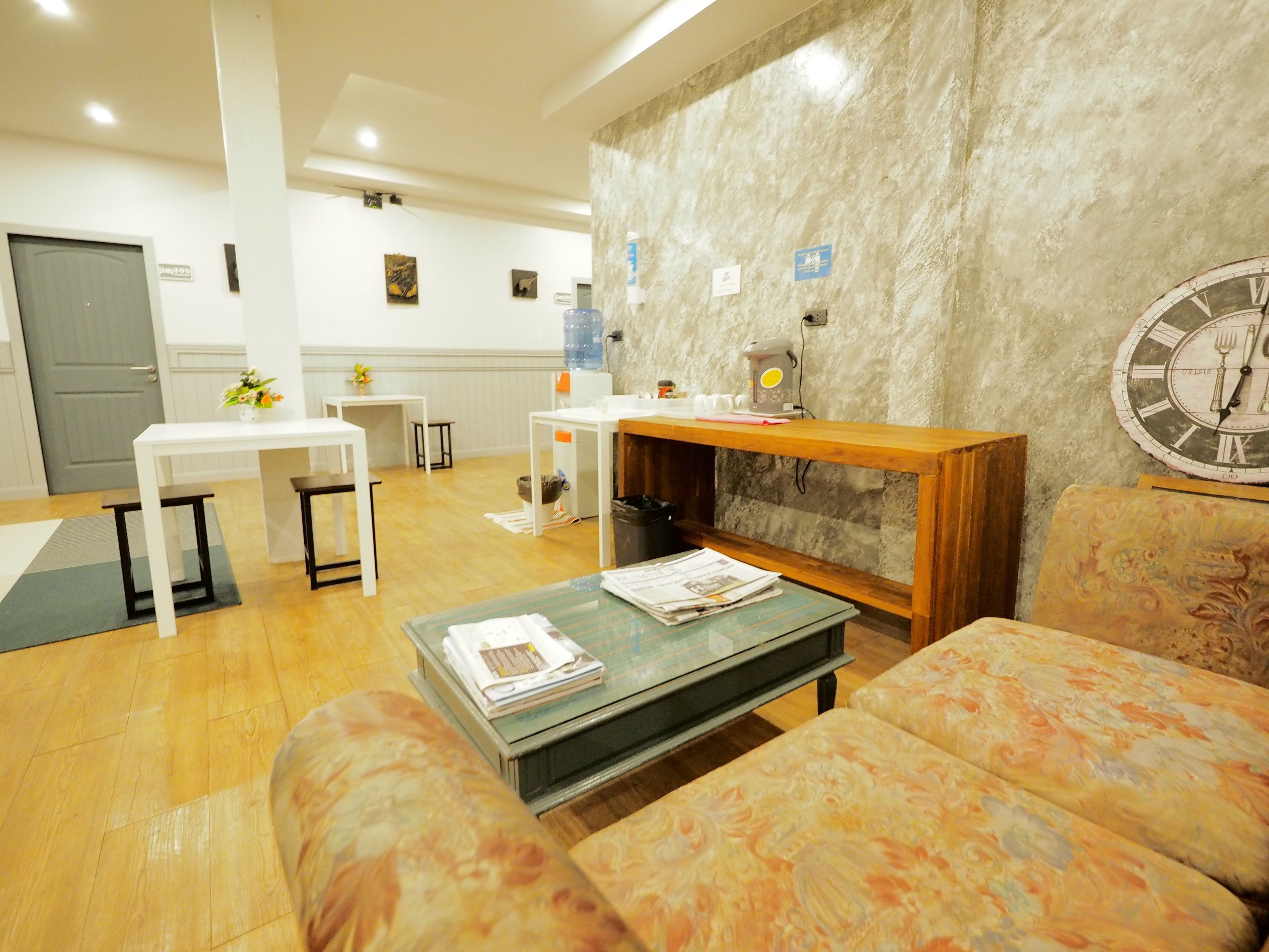 A living room with a sofa, coffee table, and a fireplace. There is a clock on the wall and a door in the background.