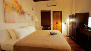 A hotel room with a bed, a television, a desk, and a large abstract painting on the wall. - Uno Chiangmai (Chiang Mai)