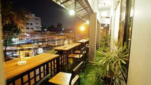 An outdoor seating area with tables and chairs, overlooking a busy street at night. - Uno Chiangmai (Chiang Mai)