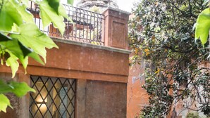 Un patio con un edificio que tiene un balcón de metal y una ventana con una reja.