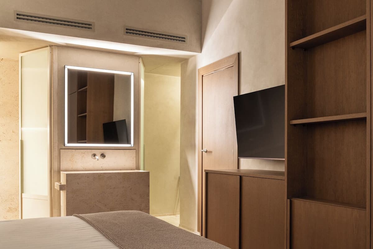 A bedroom with a bed, a wardrobe, a television, and a mirror.