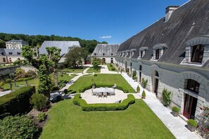 A courtyard with a central lawn, surrounded by buildings with stone facades and arched windows.