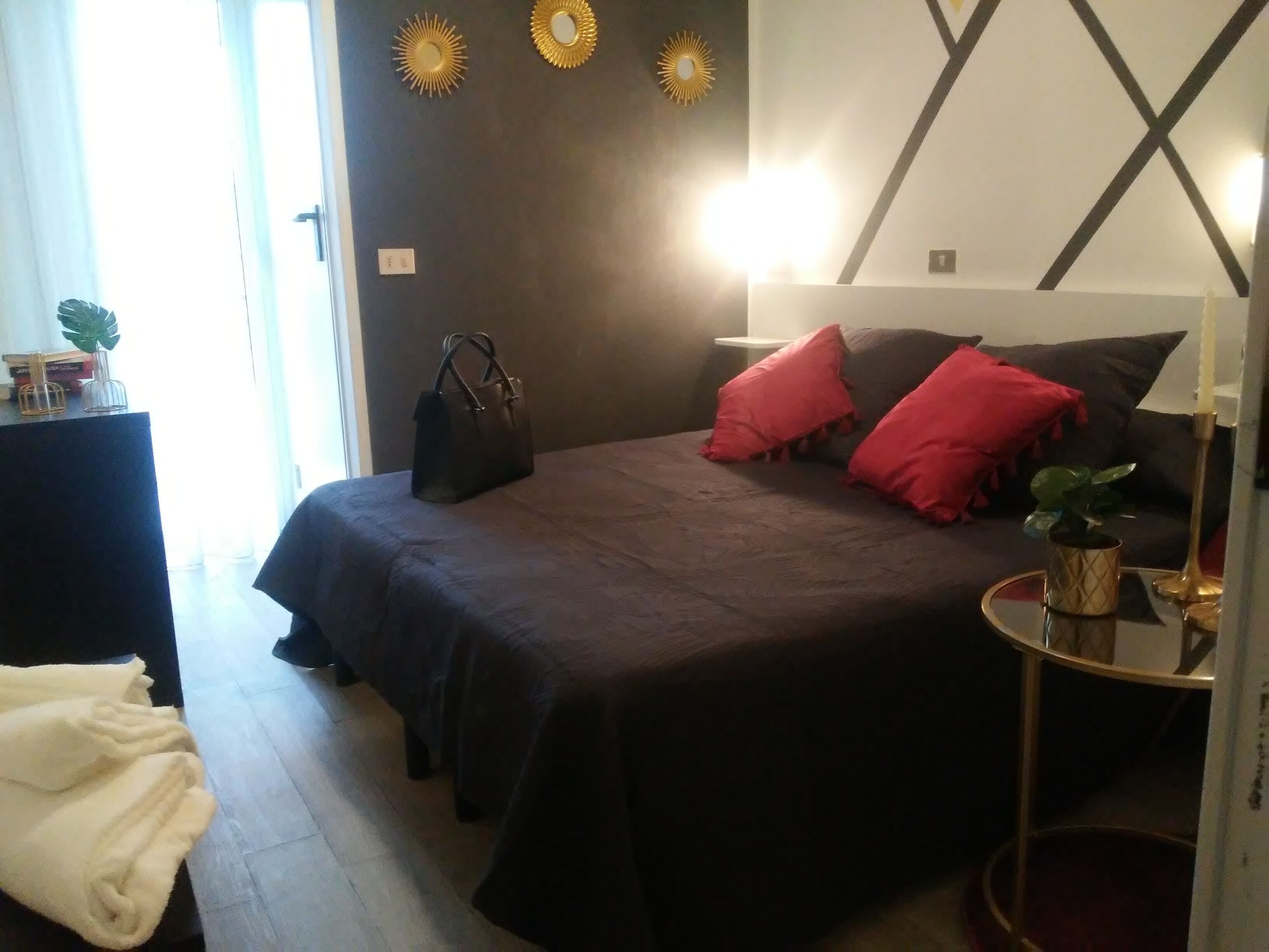A neatly arranged bedroom with a bed, pillows, a bedside table, a lamp, and a small plant.