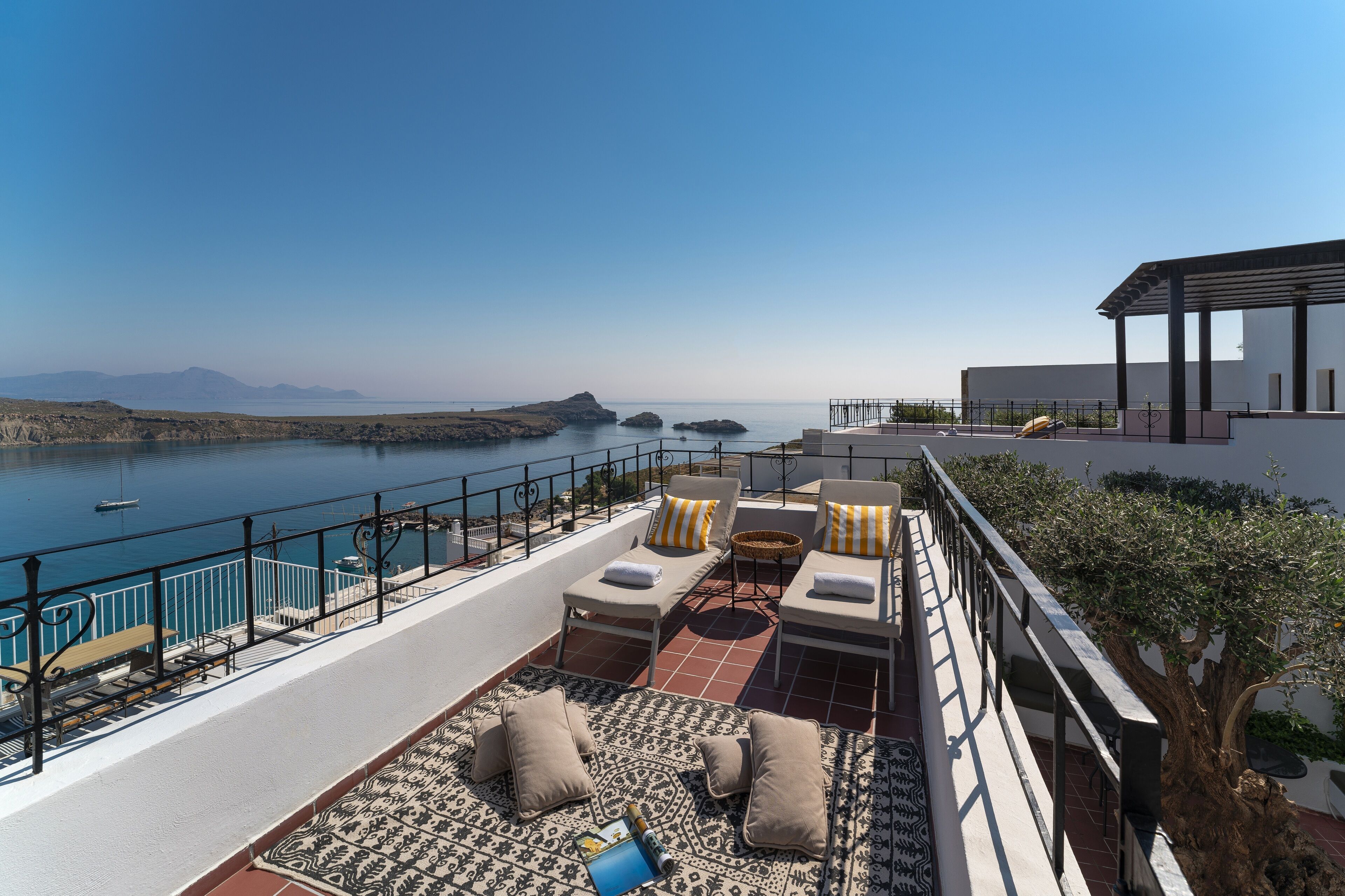 A rooftop terrace with outdoor seating, a view of the sea, and a modern building structure.